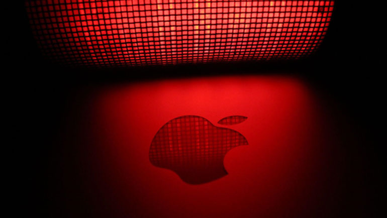 Apple logo on Macbook under a red LED light with a faded black border on either side